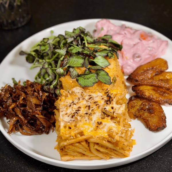 A vegan Caribbean platter with baked mac and cheese, plantains, rice, and pink salad.