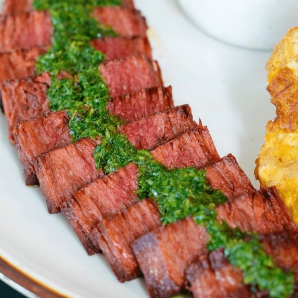 HAAM Caribbean Plant Cuisine's vegan steak, sliced and topped with vibrant green chimichurri sauce.
