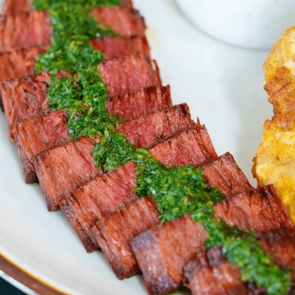 HAAM Caribbean Plant Cuisine's vegan steak, sliced and topped with vibrant green chimichurri sauce.