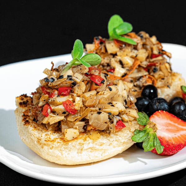HAAM's vegan Caribbean plant cuisine: two open-faced sandwiches with savory plant-based topping, berries, and strawberry.