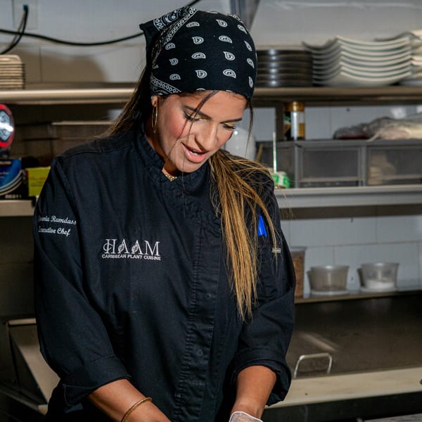 HAAM Caribbean Plant Cuisine's Executive Chef, Jevenia Ramdass, in a black chef coat and bandana.