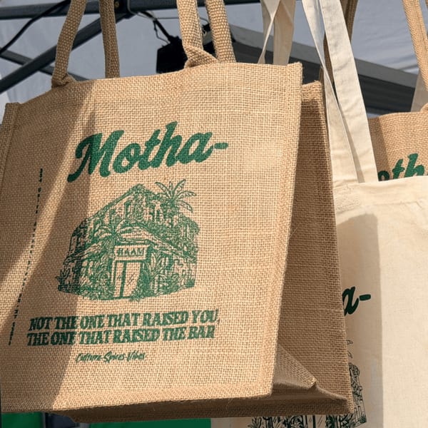 HAAM Caribbean Plant Cuisine branded burlap tote bags with green text and a building illustration.